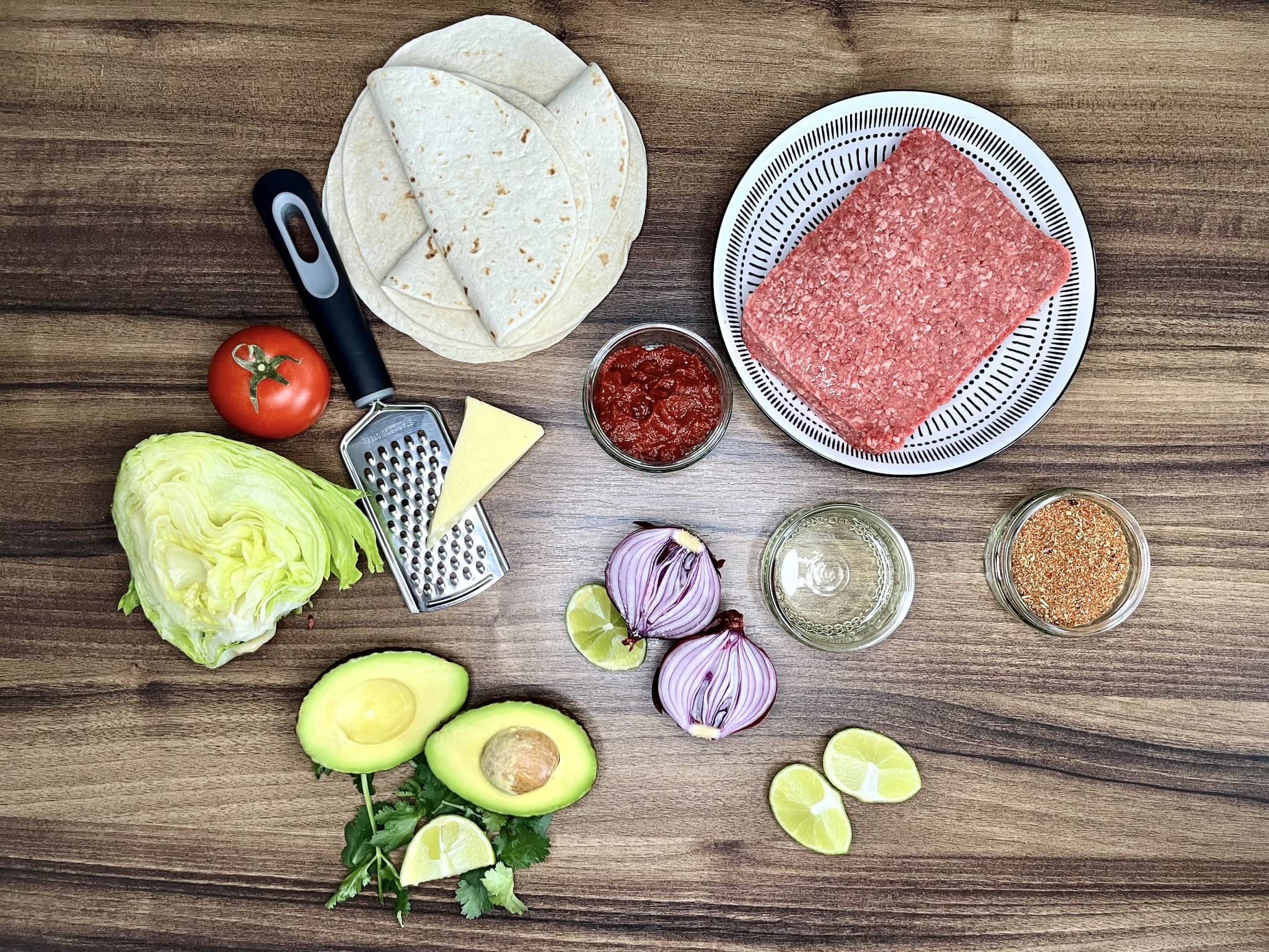 All the ingredients laid out on a tabletop, ready to make Taco-Style Beef Mince Mini Wraps