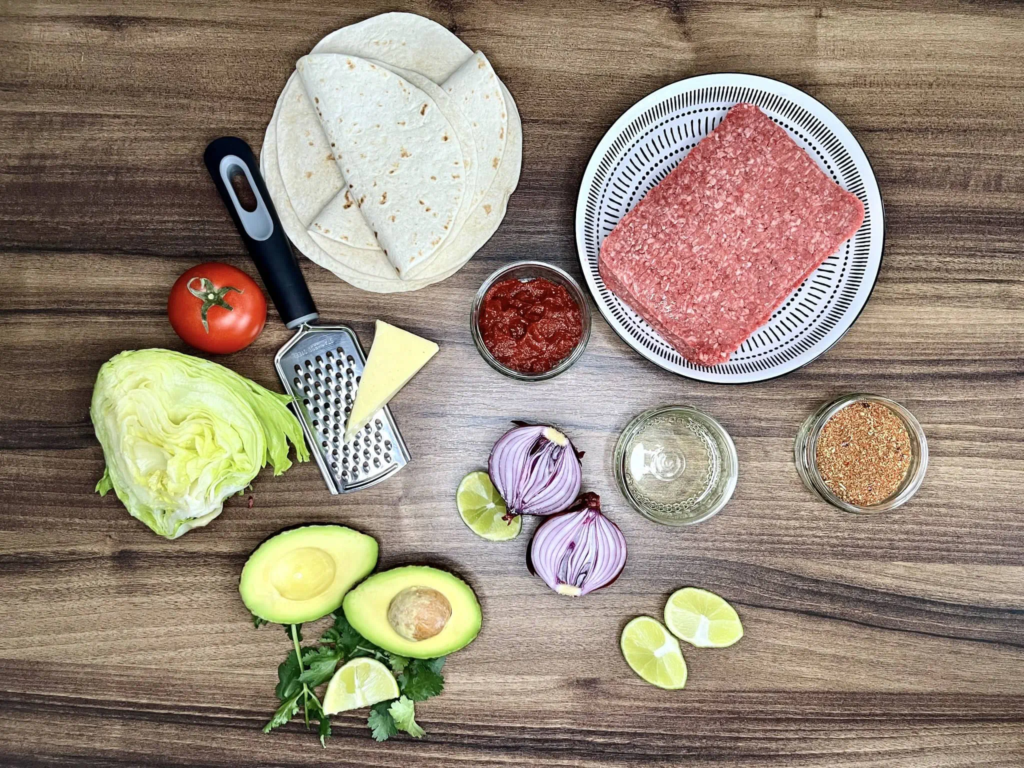 Wszystkie składniki ułożone na blacie, gotowe do przygotowania mini wrapów w stylu taco z mieloną wołowiną