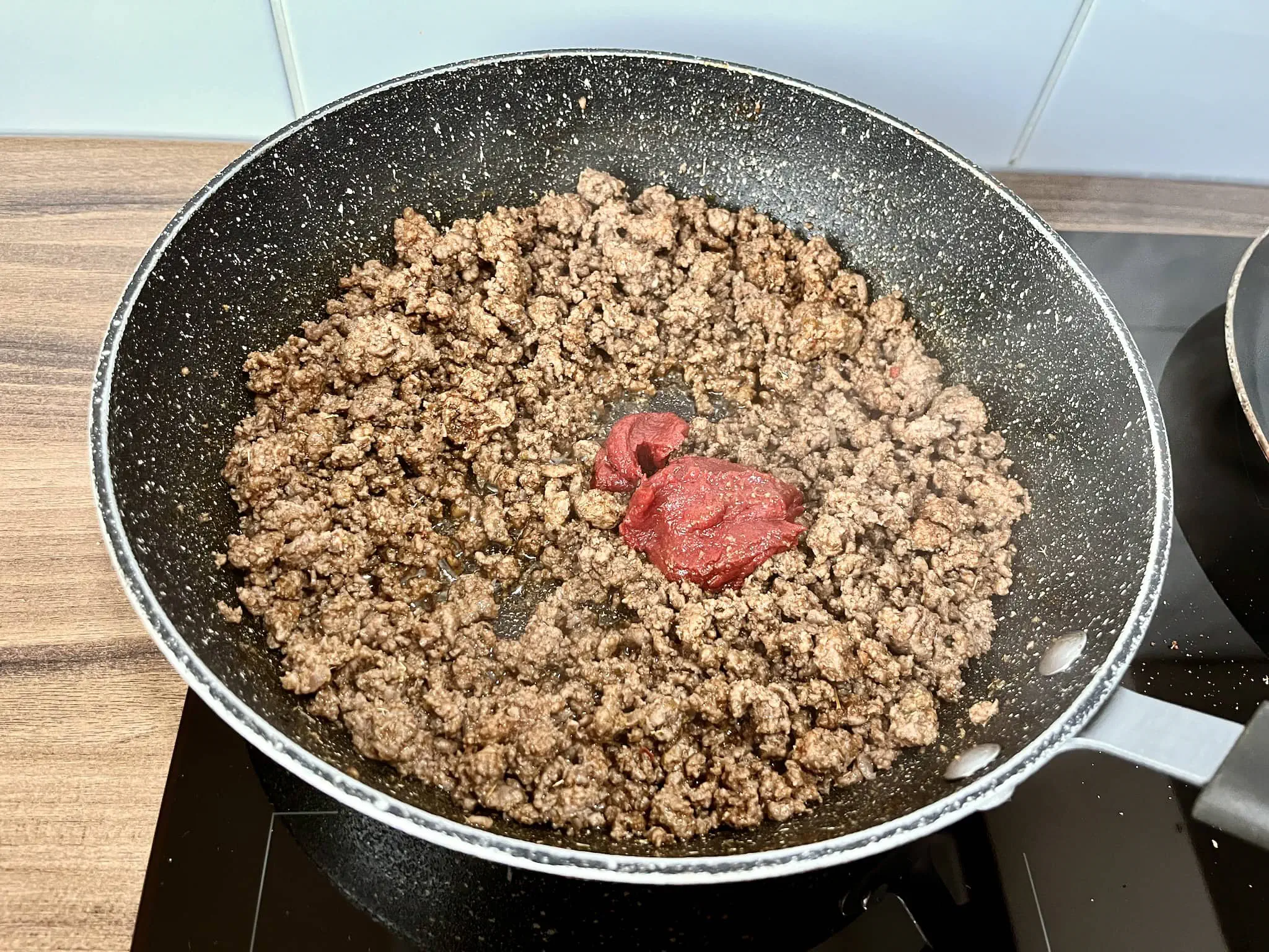 Zarumienione mięso na patelni z dodatkiem koncentratu pomidorowego