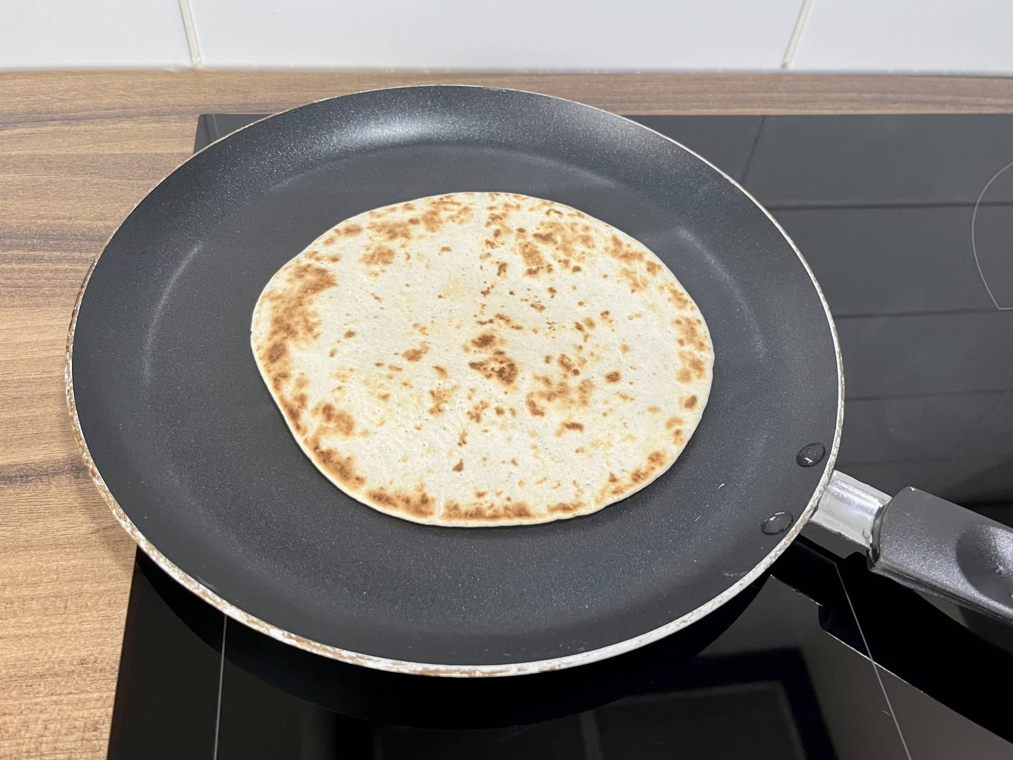 Warming and toasting a tortilla mini wrap in a flat frying pan