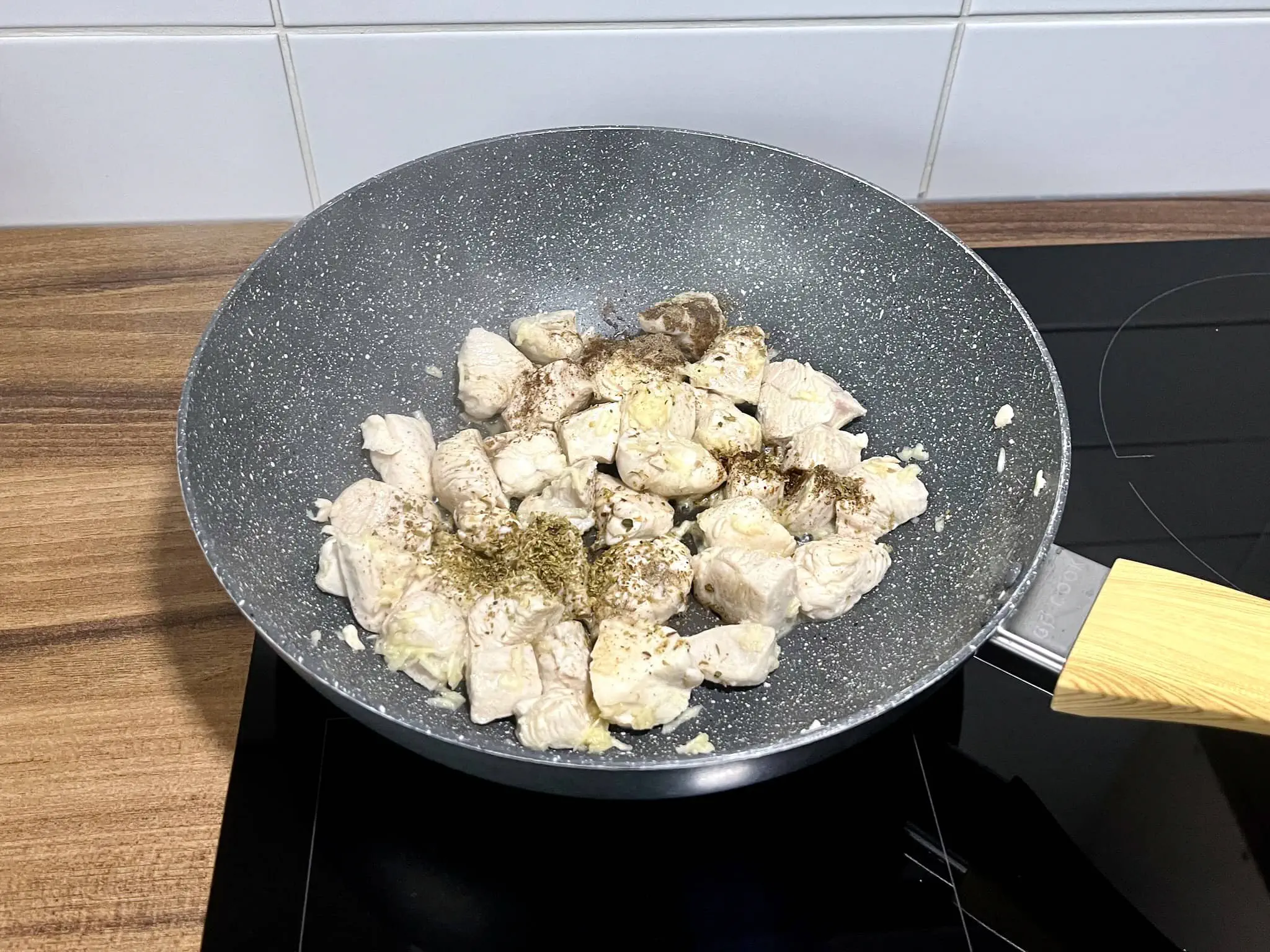 The chicken breasts are frying in a pan with added spices