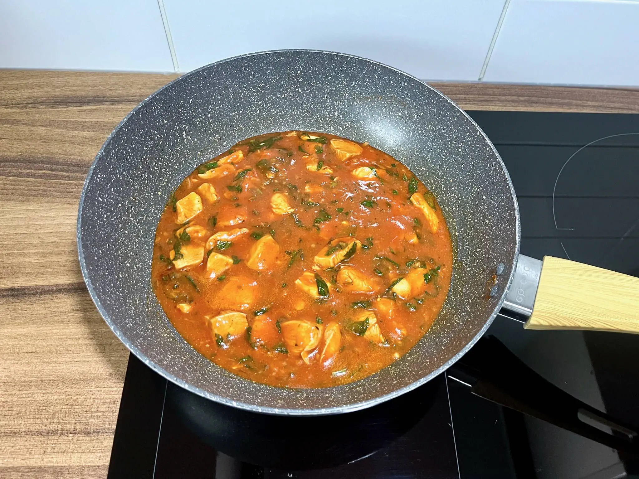 The chicken breasts are almost ready, with chopped basil added, still in the pan