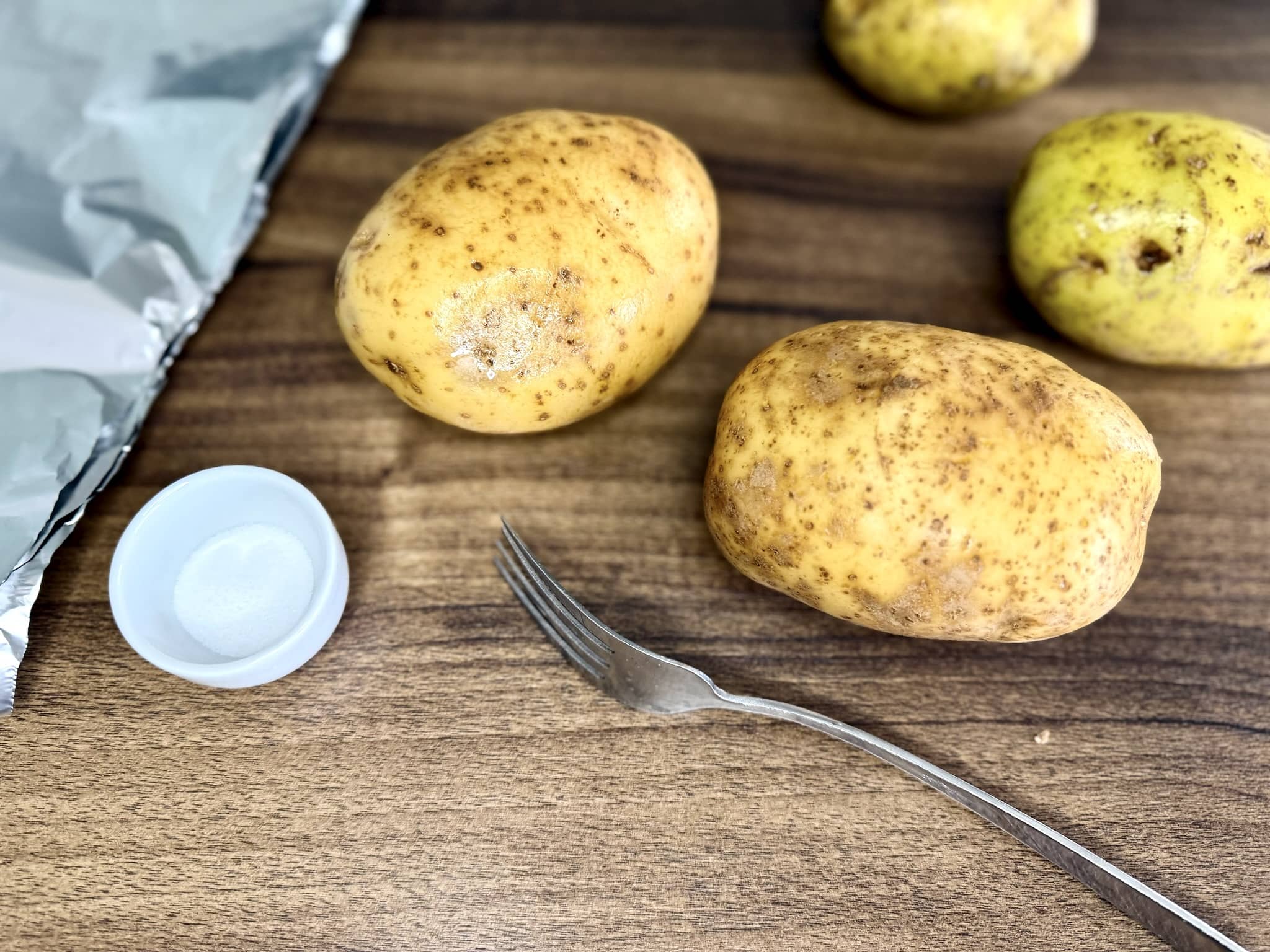 Potatoes on a tabletop with a fork and salt on the side