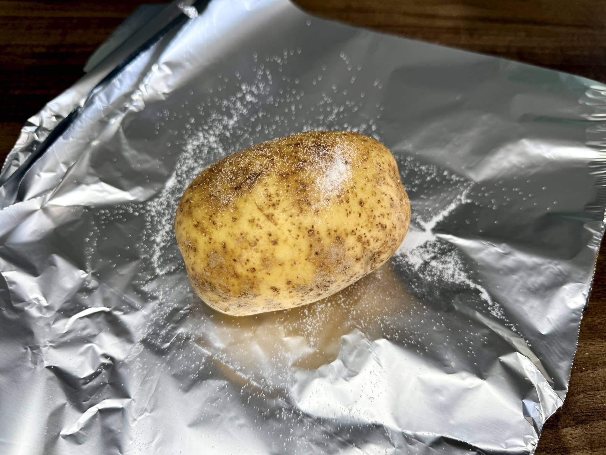 A potato on tin foil sprinkled with salt just before wrapping