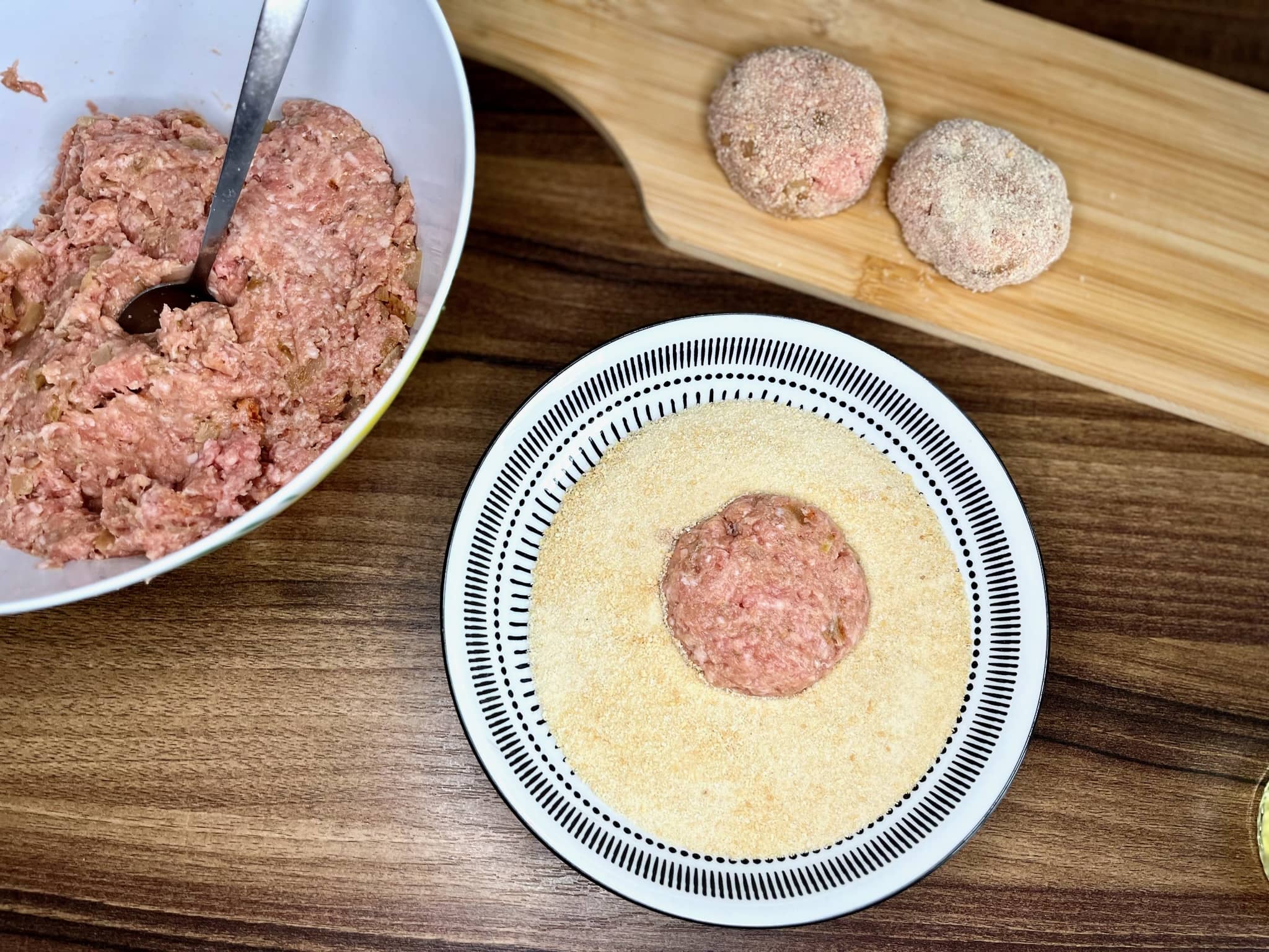 Portion of meat mixture in a bowl on top of breadcrumbs
