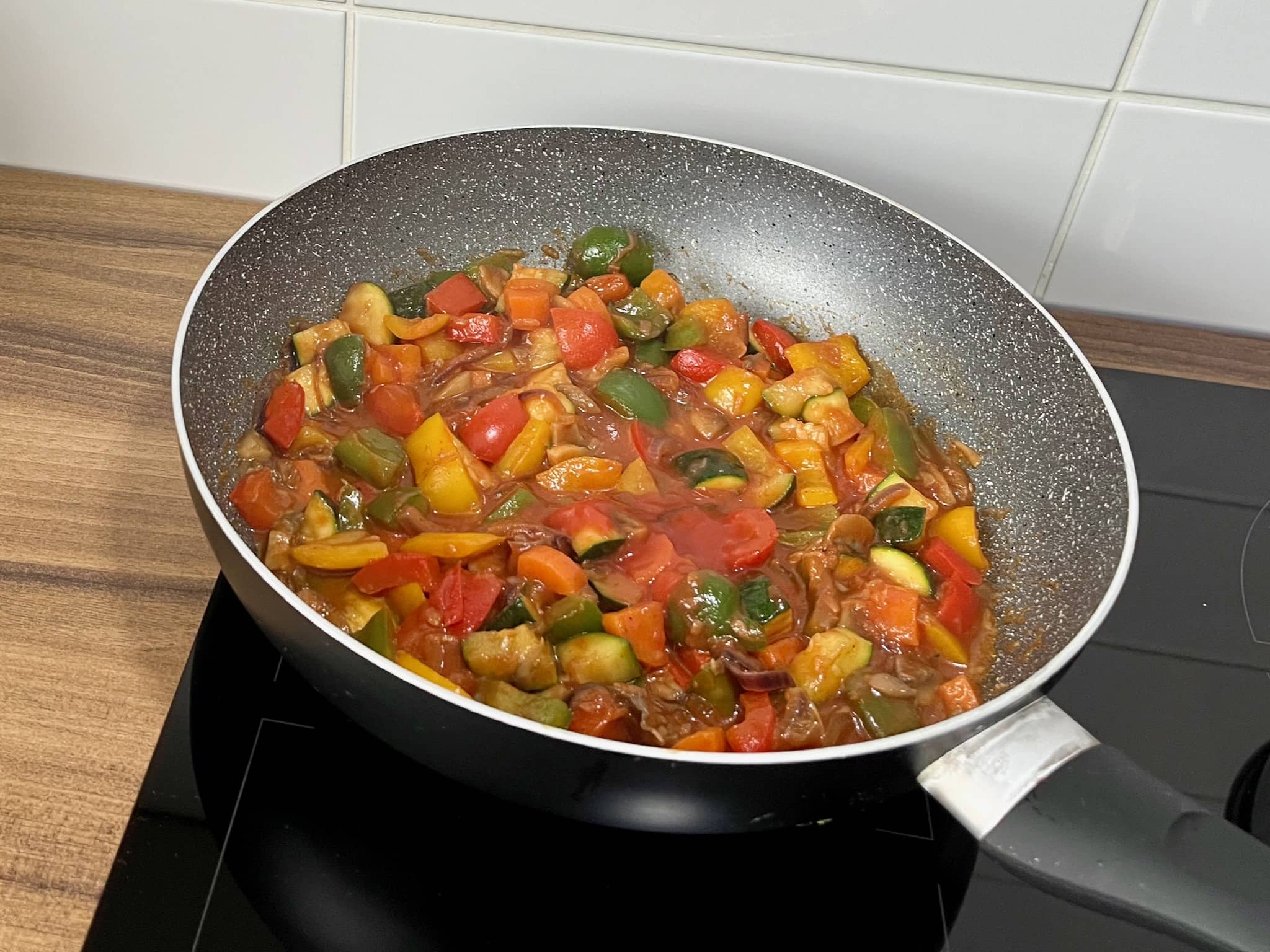 Vegetables frying in a pan with passata and water