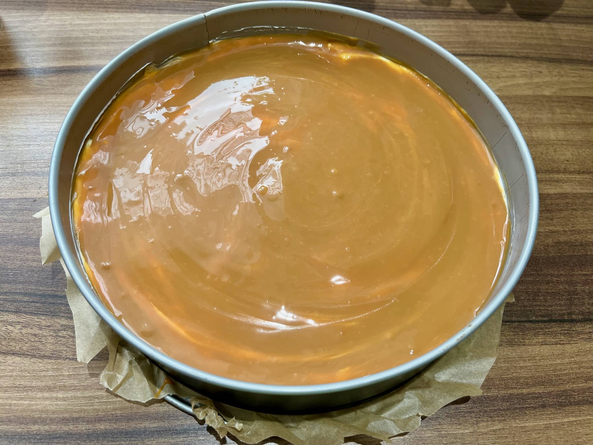 Cake tin with biscuit base with filling and caramel on the top