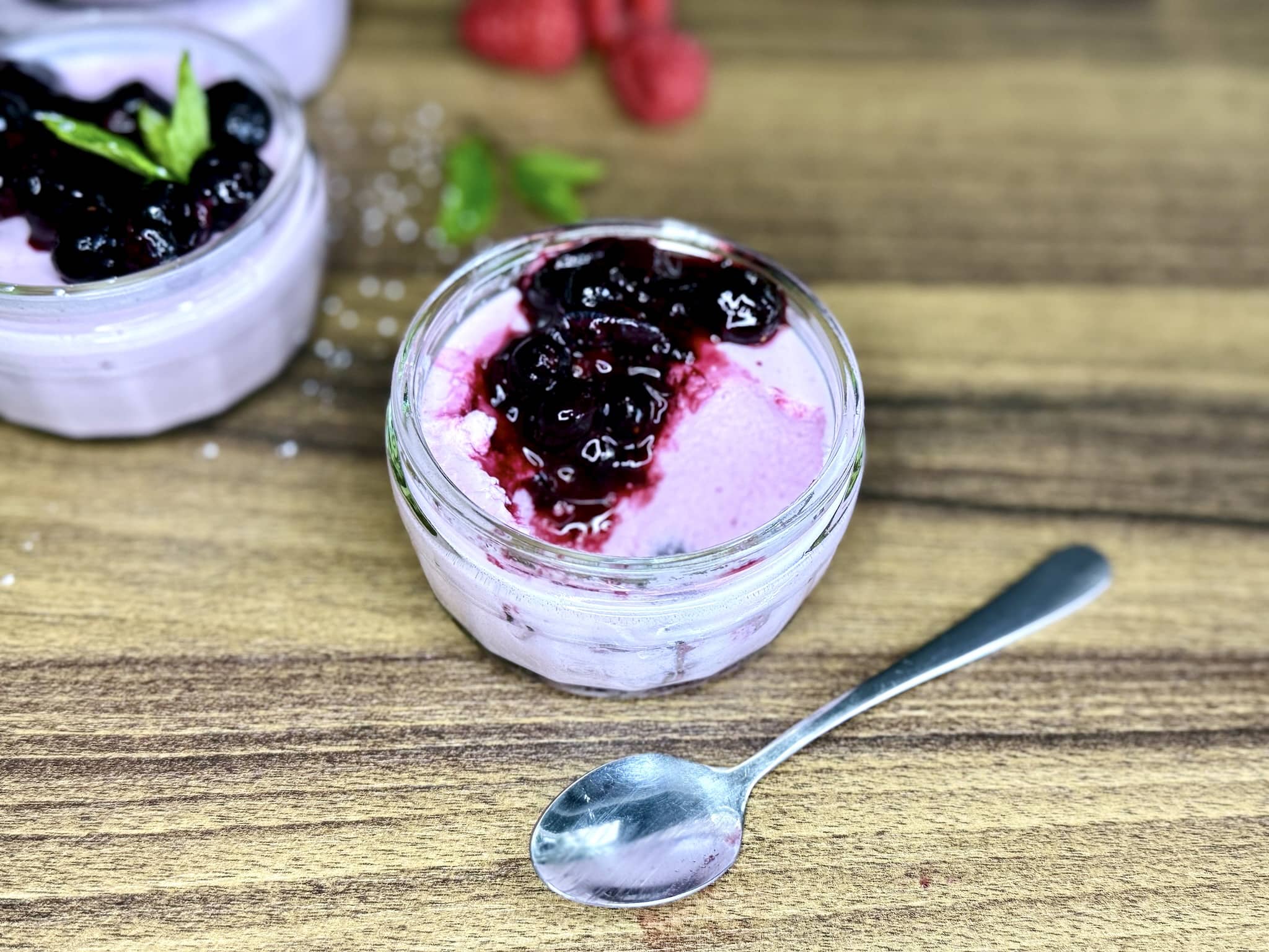Pudding z musu jogurtowego z jagodami i łyżką zanurzoną w nim